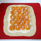 Не доходя до краев теста нанести смесь из крем - чиза и плавленого сыра, сверху выложить половинки абрикоса, присыпать его сахаром. 