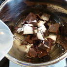 Только теперь переходим к приготовлению шоколадного мусса. Заранее готовить его не нужно! Смысл приготовления заключается в том, чтобы шоколадную массу сначала нагреть, а потом при резком охлаждении взбить ее до нужной консистенции. Итак, для мусса в сотейник выкладываем кусочки шоколада, сахар, коньяк (или другой крепкий напиток для вкуса) и наливаем воду. 