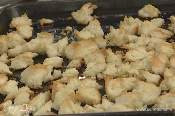 Приготовить крутоны: срезать с хлеба корку, поломать его на небольшие кусочки, сбрызнуть оливковым маслом и запекать в духовке 7–8 минут.
