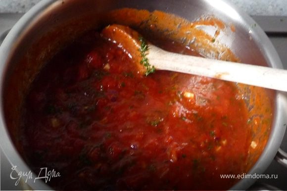 К луку и чесноку добавить томаты, посолить, поперчить, положить сахар. Вмешать итальянские травы и на среднем огне томить 15 минут.