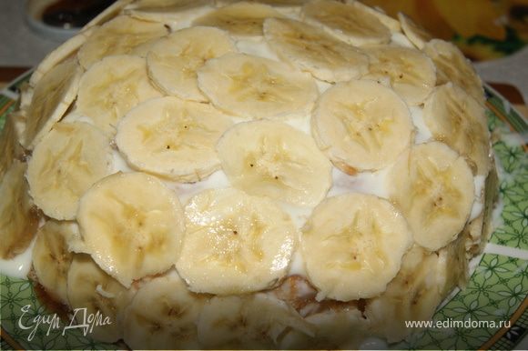 Продолжать выкладывать блины с начинкой пока не кончаться ингредиенты. Затем взять блин большого размера и накрыть им торт. Обильно смазать йогуртом и выложить бананы.