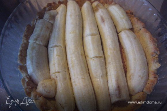На тесто выложи нарезанные напопалам бананы, сбрызни их лимонным соком, залей кремом...