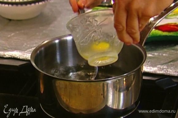 В небольшой кастрюле вскипятить воду, влить винный уксус. В две маленькие чашки разбить по яйцу. Постоянно помешивая кипящую воду с уксусом, чтобы получилась воронка, ввести одно яйцо. Через минуту-две выложить его на бумажное полотенце. Таким же образом отварить второе яйцо.