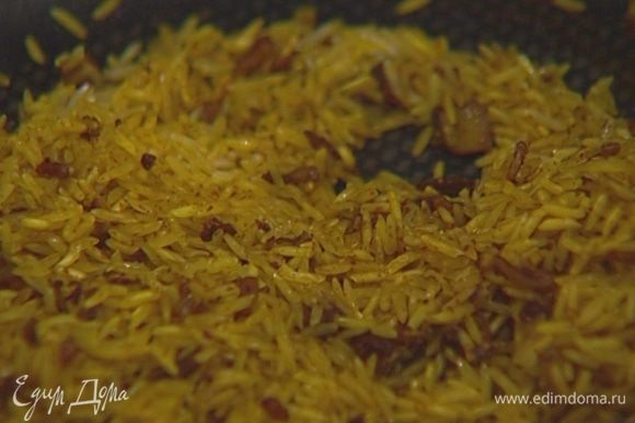Всыпать рис, помешивая, обжаривать 1-2 минуты, затем влить горячий овощной бульон, закрыть крышкой и варить рис до готовности.