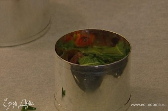Выстелить противень бумагой для выпечки, разложить на нем круглые формочки-кольца без дна и наполнить каждую формочку салатом примерно до половины.
