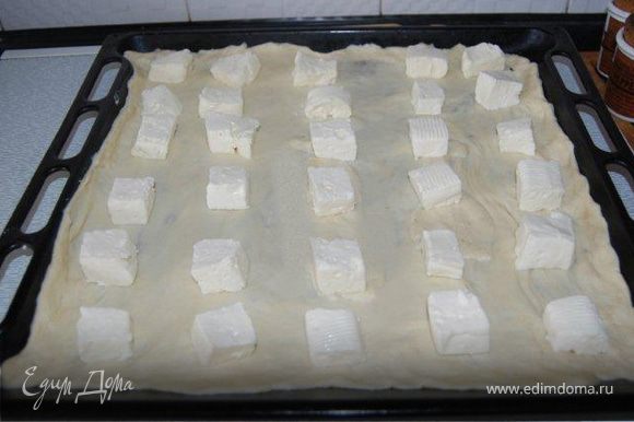 Форму для выпечки (30Х40) смазать маслом. Выложить одну половину теста. Сверху выложить нарезанный кусочками сыр.