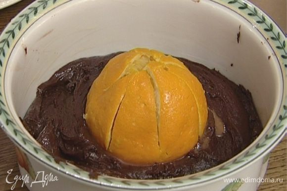 Поместить апельсин в центр формы, вдавив его наполовину в тесто.