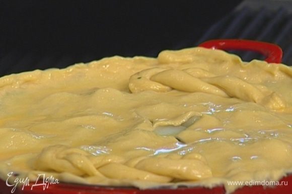 Сделать крестообразный надрез по центру пирога, смазать тесто желтком с молоком.