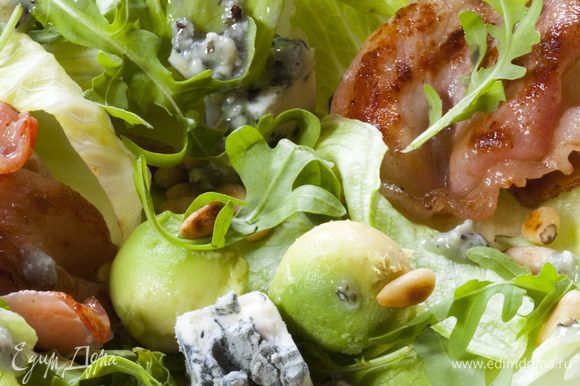 Листья салата выложить на большую тарелку, сверху посыпать кедровыми орехами, разложить бекон и сыр.