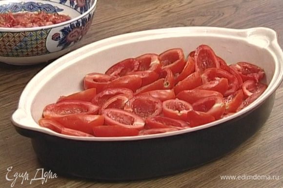 Уложить половинки помидоров в форму для запекания или в глубокий противень в один слой разрезанной стороной кверху.