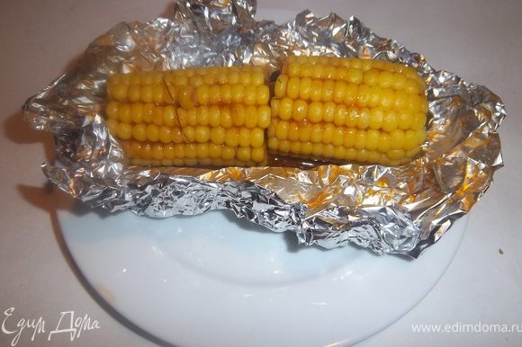 Вынуть кукурузу из фольги, положить на тарелку и полить образовавшейся при запекании соком.