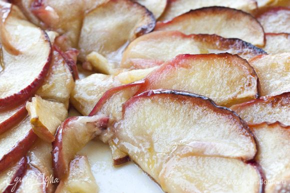 Ломтики яблок веером уложить на тесто, сверху разложить оставшееся масло, присыпать оставшимся сахаром и корицей.