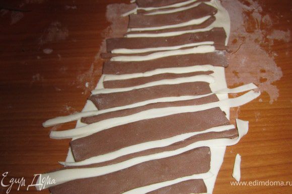Вырезать полоски из белой и шоколадной мастики, выложить на раскатанную мастику.
