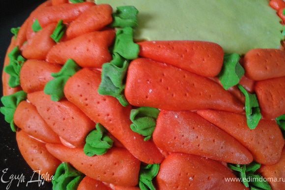 Лепим морковки. Их можно сделать заранее. Так как морковки в 3D, то они могут потянуть много мастики и занять много места. Их можно сделать пустотелыми половинками. Я делала из минимума мастики. Внутрь - миндаль. У него такая подходящая форма. Зеленые хвостики и черточки - зубочисткойПриклеиваем морковки по кругу, начиная внизу.