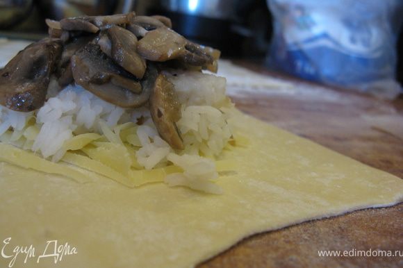 На каждую лепешку выложить порцию тертого сыра, на него - вареный рис, затем кусочек обжаренной рыбы и сверху грибы.