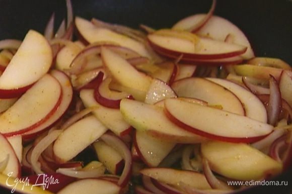 В сковороду с маслом, где обжаривался бекон, выложить яблоко и лук, посолить, поперчить и, помешивая, обжаривать 7−8 минут, пока лук не станет золотистым.