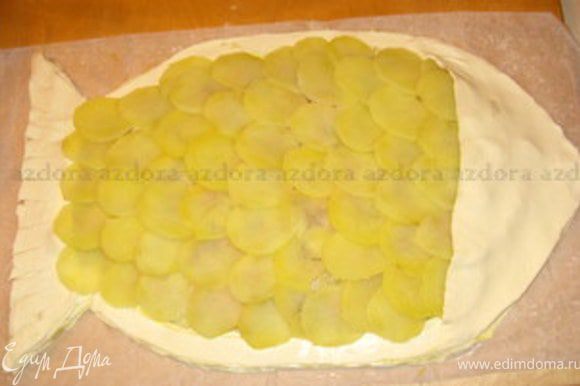 Из ломтиков картофеля сделать чешую.Добавить голову и хвост рыбки. Сделать глаз из маслины. Смазать часть рыбки из слоёного теста желтком, который останется отяйца, а картофель оросить оливковым маслом.Чтобы он лучше подрумянился, присыпать его тёртым пармиджано. Запекать при 180° около 30 минут.Через 30 минут покрошить сливочное масло на картофель и запекать ещё минут10.