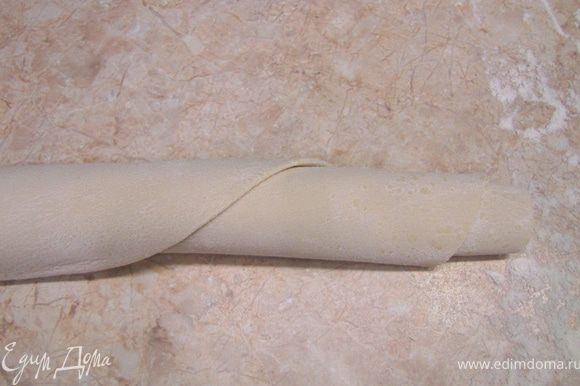 Посыпьте обильно мукой тесто. Скатайте лист теста в рулон. Так будет легче нарезать лапшу.
