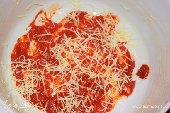Смазываем керамическую форму кусочком сливочного масла. На дно формы выкладываем немного томатного соуса, сверху присыпаем тертым сыром.