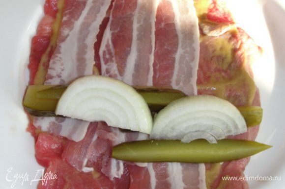 Для начинки 1 выкладываем на кусочек мяса бекон по 2-3 кусочка, порезанные на длинные полосочки огурчики, полукольца лука.