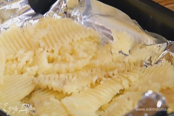Небольшой противень выстелить фольгой, разложить картофель так, чтобы получился пласт, и сбрызнуть оливковым маслом.