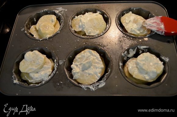 Разогреть духовку до 200°C. Выложить картофель, нарезанный пластинками, посолить и поперчить каждый слой. Смазать сметаной или сливками сверху. Посыпать сыром.