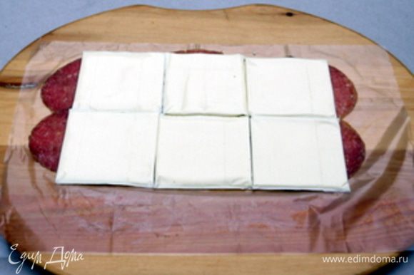 На рабочей поверхности ,накрытой пергаментом, разложить тонко нарезанные ломтики салями. Сверху на салями распределить пластинки сыра.