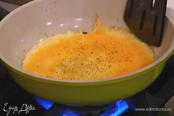 В сковороду, где готовился бекон, вылить взбитые яйца, посолить, поперчить и жарить омлет до готовности (он должен получиться тонким), а затем снять его со сковороды.