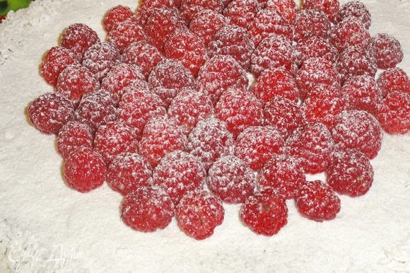 Когда ганаш застынет, украсьте торт ягодами малины и посыпьте сахарной пудрой (по желанию)