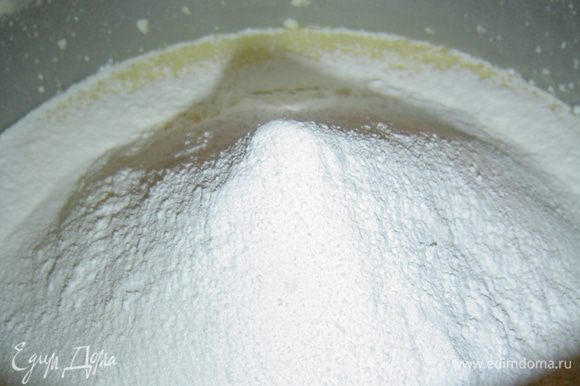 Следующим этапом вливаем молоко, добавляем ванильный сахар, просеянную муку с разрыхлителем и аккуратно перемешиваем ложкой.