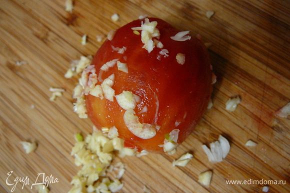 Чеснок мелко порубить и обвалять помидоры в мелко рубленном чесноке.