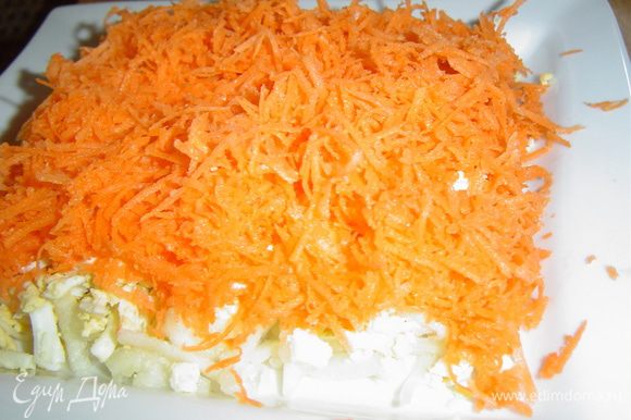 Морковь очищаем, натираем на мелкой терке и выкладываем на яичный слой, смазываем соусом - это четвертый слой.