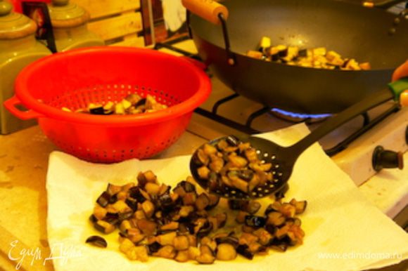 Обжарить баклажаны на большом количестве оливкового масла. Достать шумовкой из масла и перенести на блюдо, накрытое бумажными полотенцами, чтобы они впитали излишек масла.