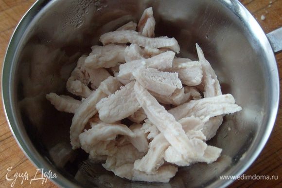 Нарезать соломкой отваренную куриную грудку. Выложить курицу в кокотницу или форму для запекания, сверху выложить грибы.