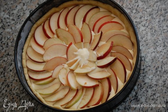 Залить тесто творожным кремом. Сверху выложить дольки яблок, слегка вдавливая их в крем.