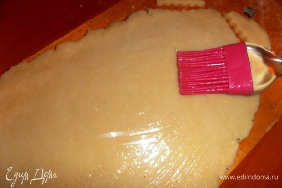 Затем раскатываем на доске тесто толщиной примерно в 0,5 см и смазываем слегка взбитым белком.