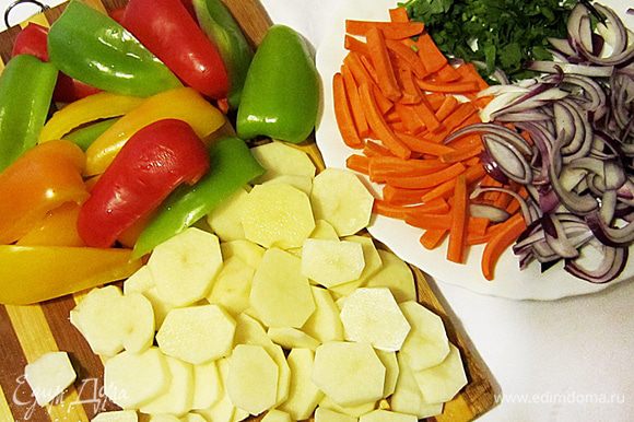Подготовить овощи: картофель нарезать кружочками, морковь брусочками, каждый перец нарезать на 6 долек (удалив предварительно сердцевины), лук очистить и крупно нарезать. Петрушку порубить.