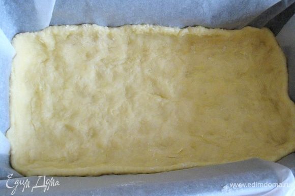 В форму, застеленную пекарской бумагой, выкладываем тесто и равномерно распределяем по всему дну, делая небольшие бортики. (В этот раз я использовал прямоугольную форму 24х13 см, но можно взять и обычную, разъёмную на 20 см.)