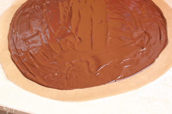 Делаем наше покрывало... Берем бумагу и вырезаем круг диаметром 35 см. Внутри его отступаем на 2 см от края, рисуем еще один круг. На всякий случай я приложила свой круг к торту, проверила подойдет или нет... немного замазав конечно его... Теперь разогреваем шоколад на водяной бане, шоколад беру темный, 55% какао. Выливаем шоколад на бумагу и размазываем не доходя 2 см до края. Даем ему остыть на столе примерно минут 15.
