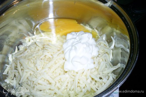 В отдельную емкость натираем сыр на крупной терке, добавляем сметану, яйцо и белок. Желток оставляем для смазывания верха пирога.
