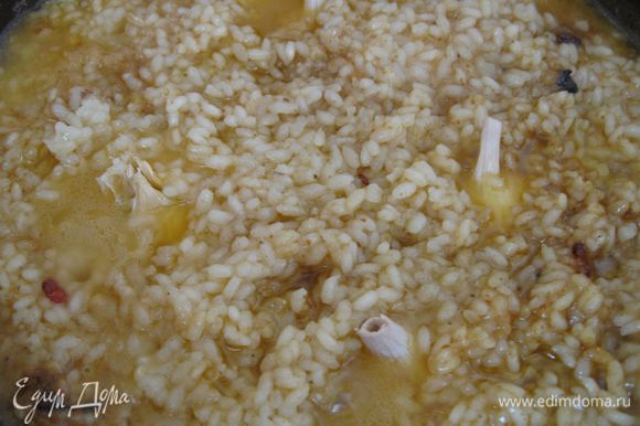 Через 10-15 минут, когда вода с поверхности риса почти выкипит, сделать лунки и «посадить» чеснок. Закрыть крышкой, сделать маленький огонь на 5 минут. Выключить газ.
