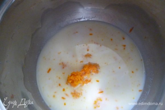 От общего количества молока отлить половину стакана в отдельную посуду, добавить натертую цедру апельсина, сахар и довести до кипения. Накрыть крышкой и дать остыть.