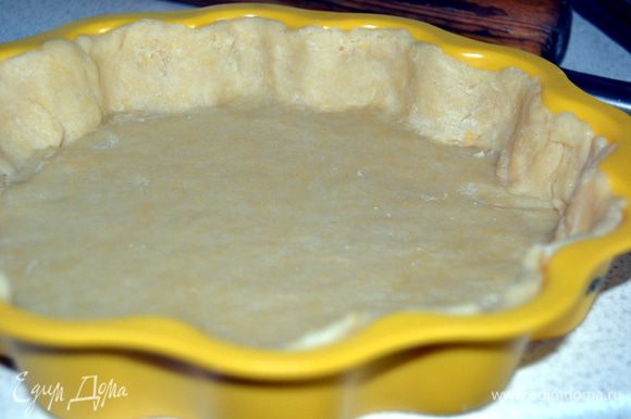 Охлажденное тесто раскатать на присыпанном мукой столе толщиной 4-5 мм. Форму смазать маслом и уложить тесто, сделав бортики.