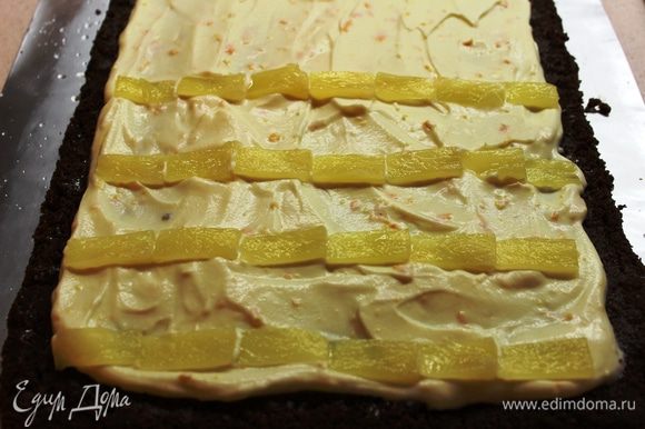 Выложить крем ровным слоем, оставив по краям примерно по 1,5 см. Кольца ананасов разрезать вдоль пополам, чтобы они были тоньше. Затем нарезать их тонкими пластинками и разложить поперечными полосками поверх крема