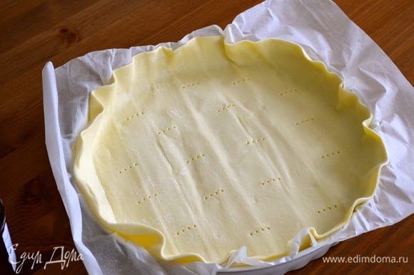Выложить готовое слоеное тесто (вместе с бумагой) в форму, сформировать бортик и наколотить вилкой, чтобы тесто не вздулось при выпечки.