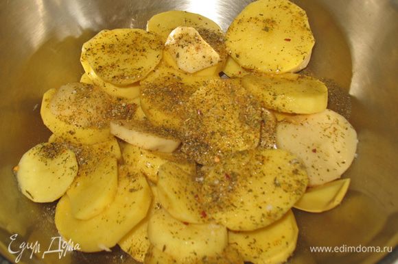 Складываем картофель в емкость, поливаем растительным маслом, добавляем соль, черный перец и специи. Хорошо перемешиваем руками, следя за тем чтобы каждый ломтик был покрыт маслом.