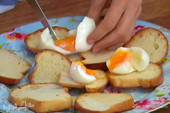 Яйца разломить руками и выложить на тосты, на яйца поместить ломтики семги, посыпать зеленым луком, сверху разложить спаржу.