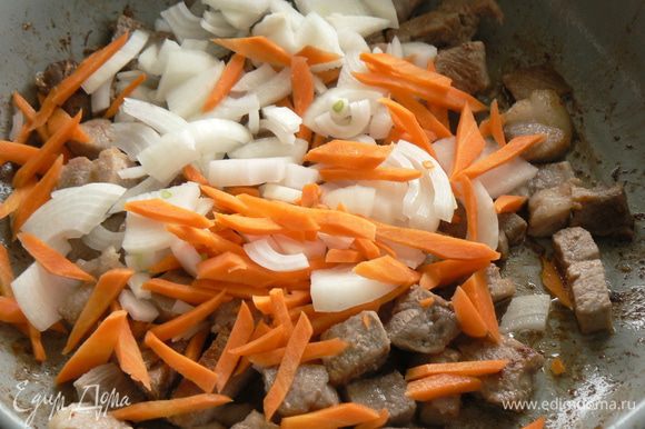 Мясо режем кубиками и выкладываем на сковородку. Жарим на оливковом масле, помешивая, пока не подрумянится. Добавляем нарезанный полукольцами-кольцами лук и соломкой морковь, готовим на среднем огне, помешивая, около 5 минут.