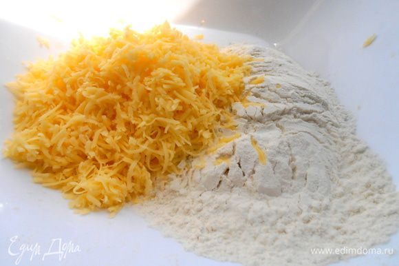 Муку (сначала не всю,так как много зависит от сорта сыра,его мягкости) соединить с разрыхлителем и всыпать сыр.