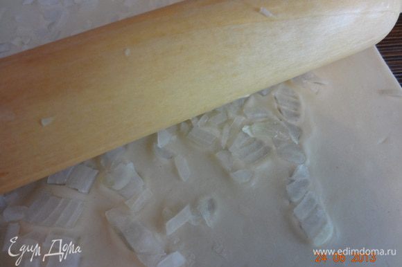 Отдохнувшее тесто (должно стать эластичным и мягким) разделить на две части, раскатать сначала одну в пласт толщиной 1-2 мм, равномерно распределить по нему половину измельченного лука и скалкой вдавить в тесто.